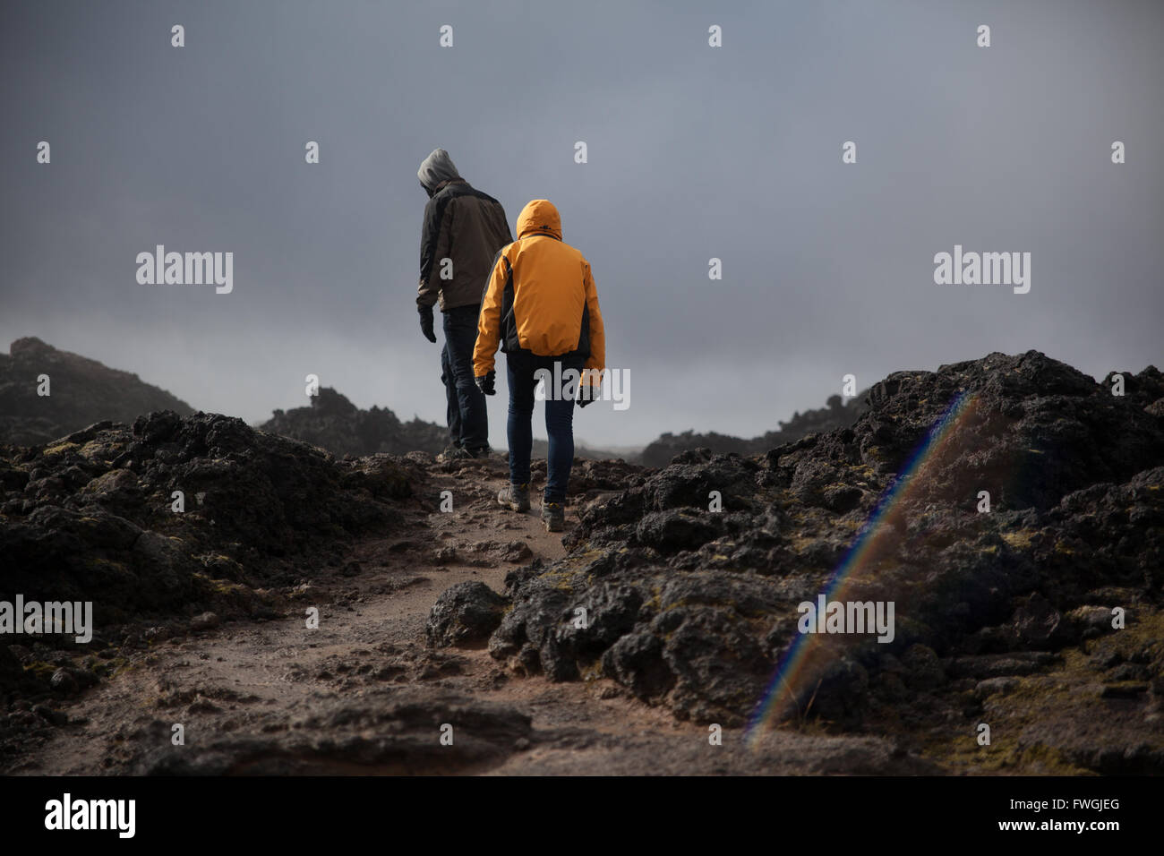 Full Length Rear View Of Tourist Walking On Arid Landscape Against Cloudy Sky Stock Photo