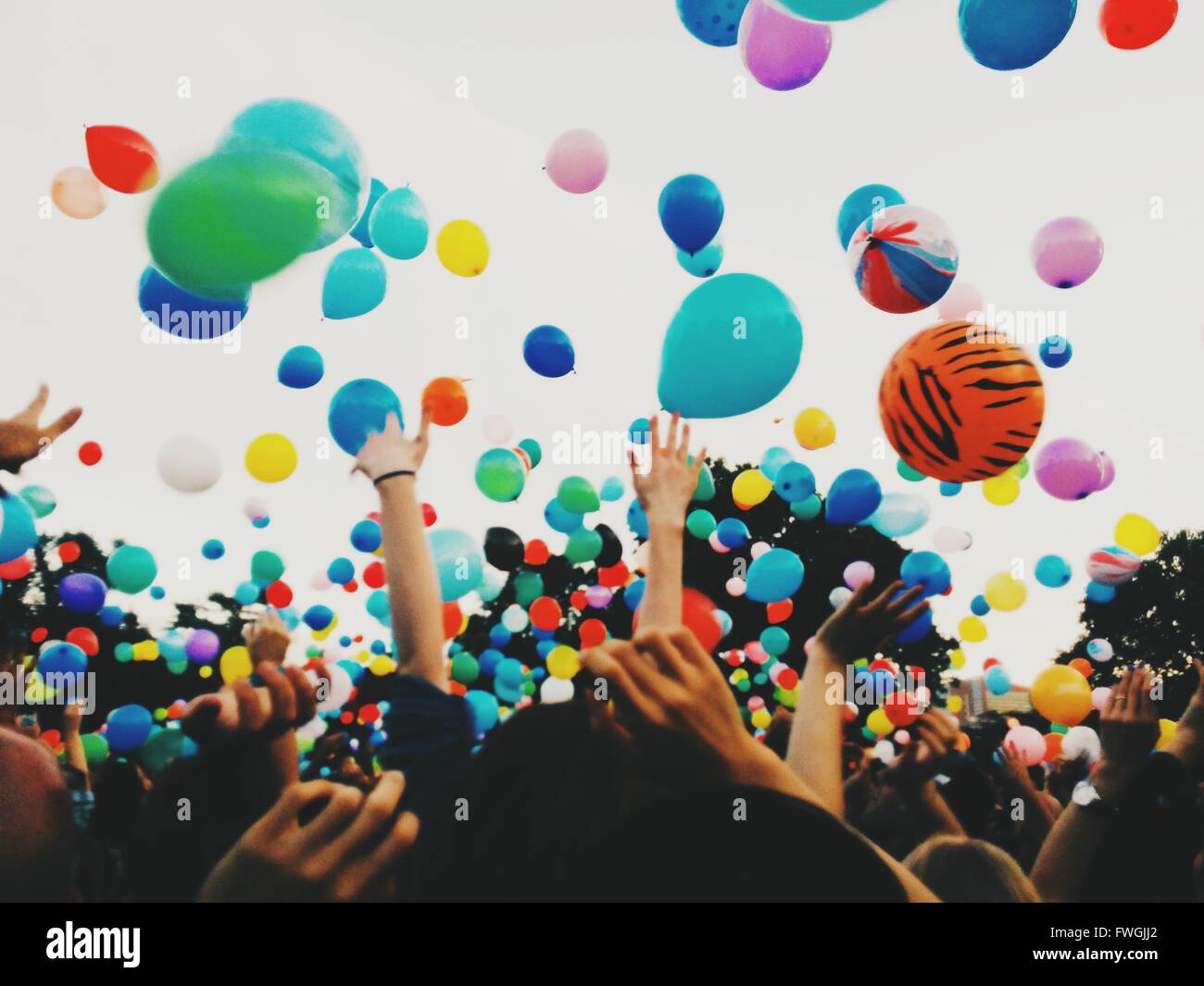 Crowd throwing colorful balloons against sky during festival Stock Photo