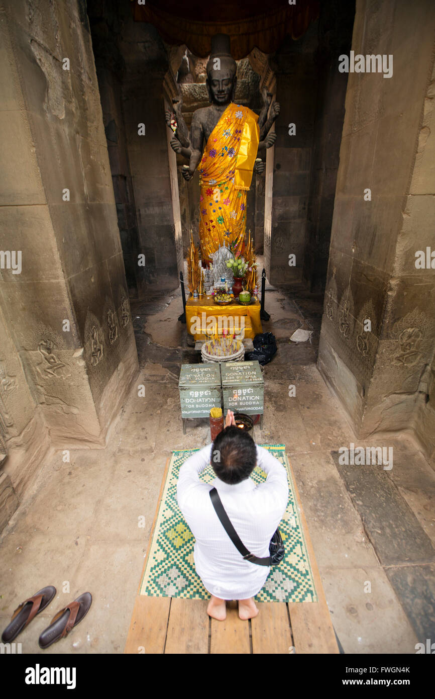 A man praying in front of a statue of Buddha, Angkor Wat, Siem Reap