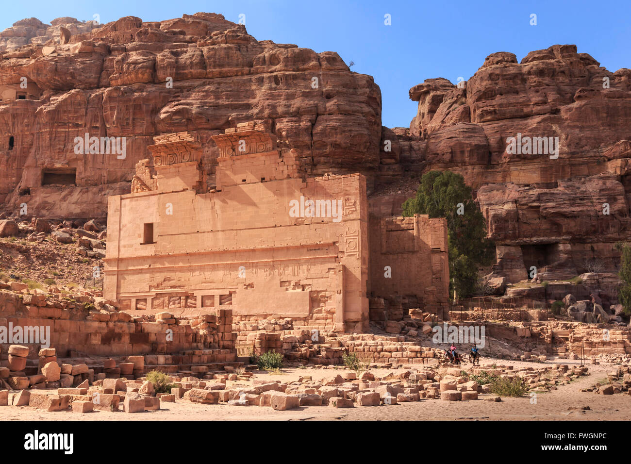 Local men on donkeys pass Qasr al-Bint temple, City of Petra ruins, Petra, UNESCO World Heritage Site, Jordan, Middle East Stock Photo