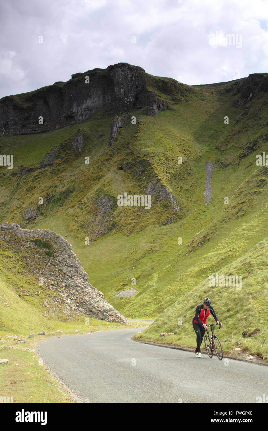 A cyclist pushes his bike up Winnats Pass, a steep limestone cleft in Castleton,  Peak District, Derbyshire England UK Stock Photo