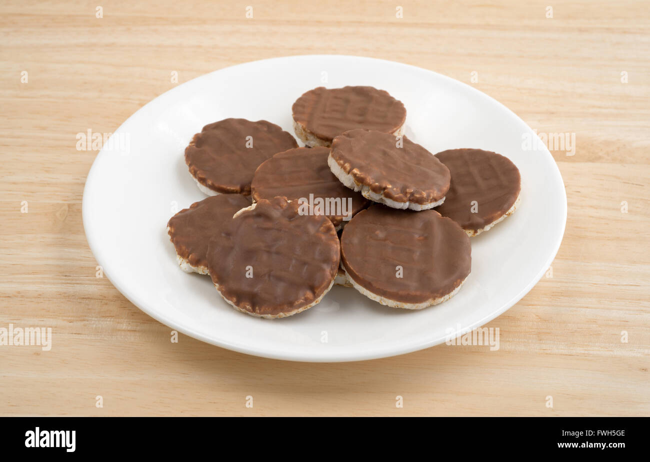 Side view of a group of organic rice cookies with milk chocolate icing on a wood table top. Stock Photo