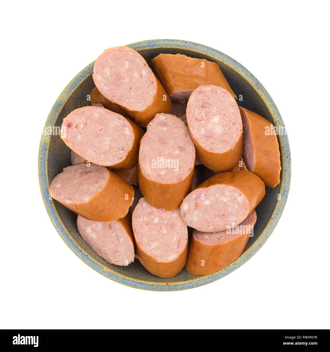 Top view of several slices of reduced calorie kielbasa sausage in an old stoneware bowl isolated on a white background. Stock Photo