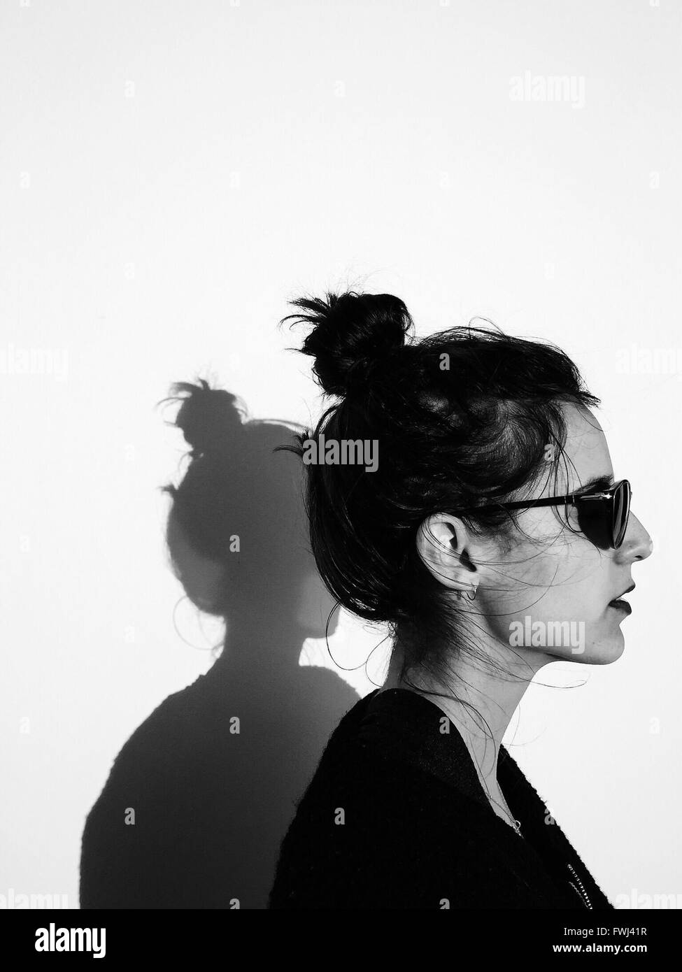 Profile View Of Woman Wearing Sunglasses Against Wall Stock Photo