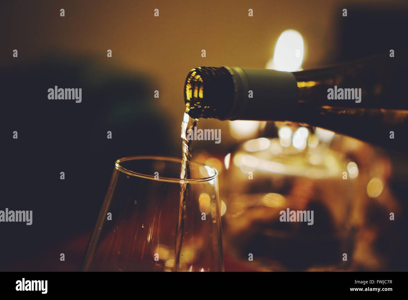 Close-Up Of White Wine Pouring In Glass During Christmas Stock Photo