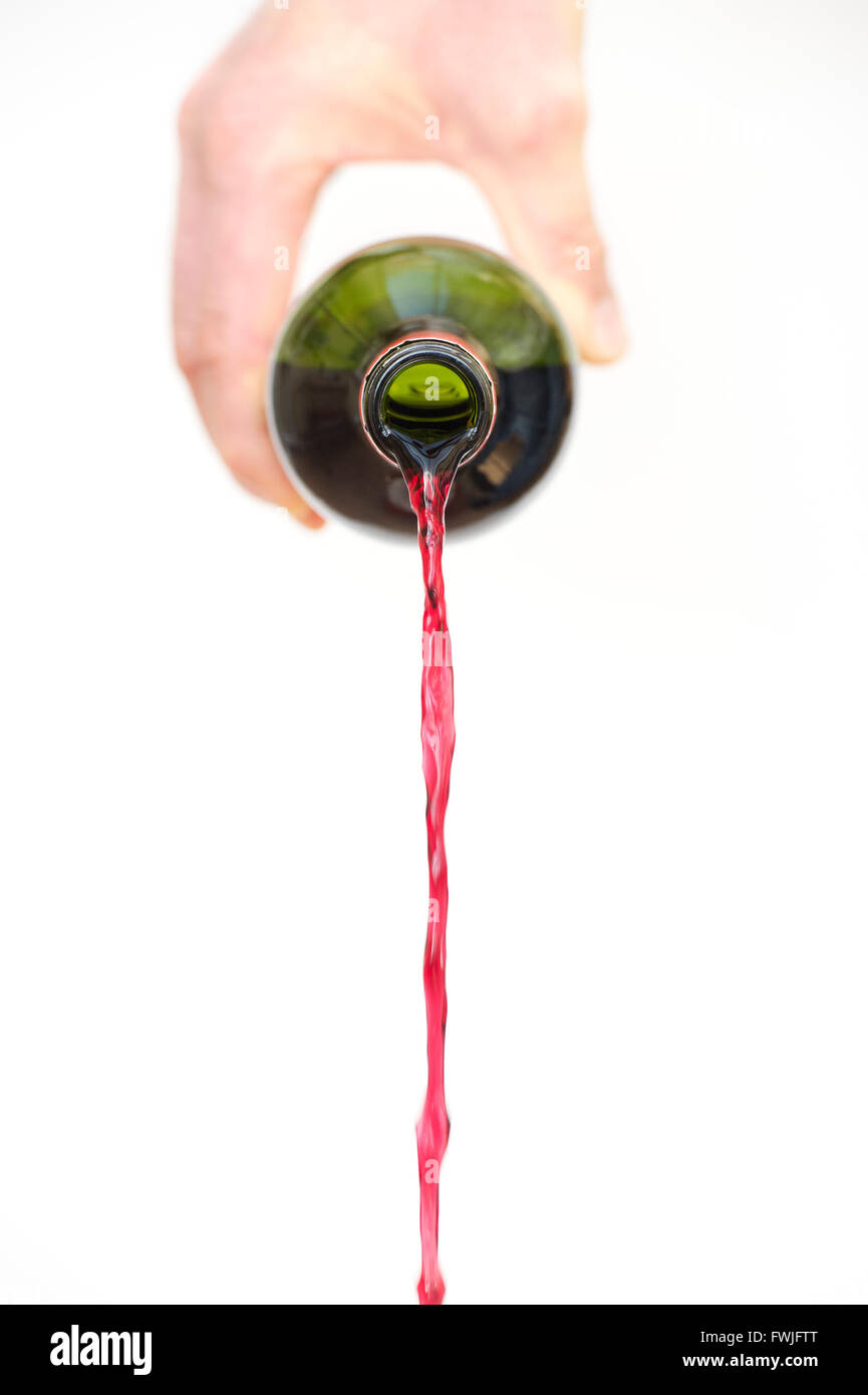 Hand pouring red wine from a bottle against white background Stock