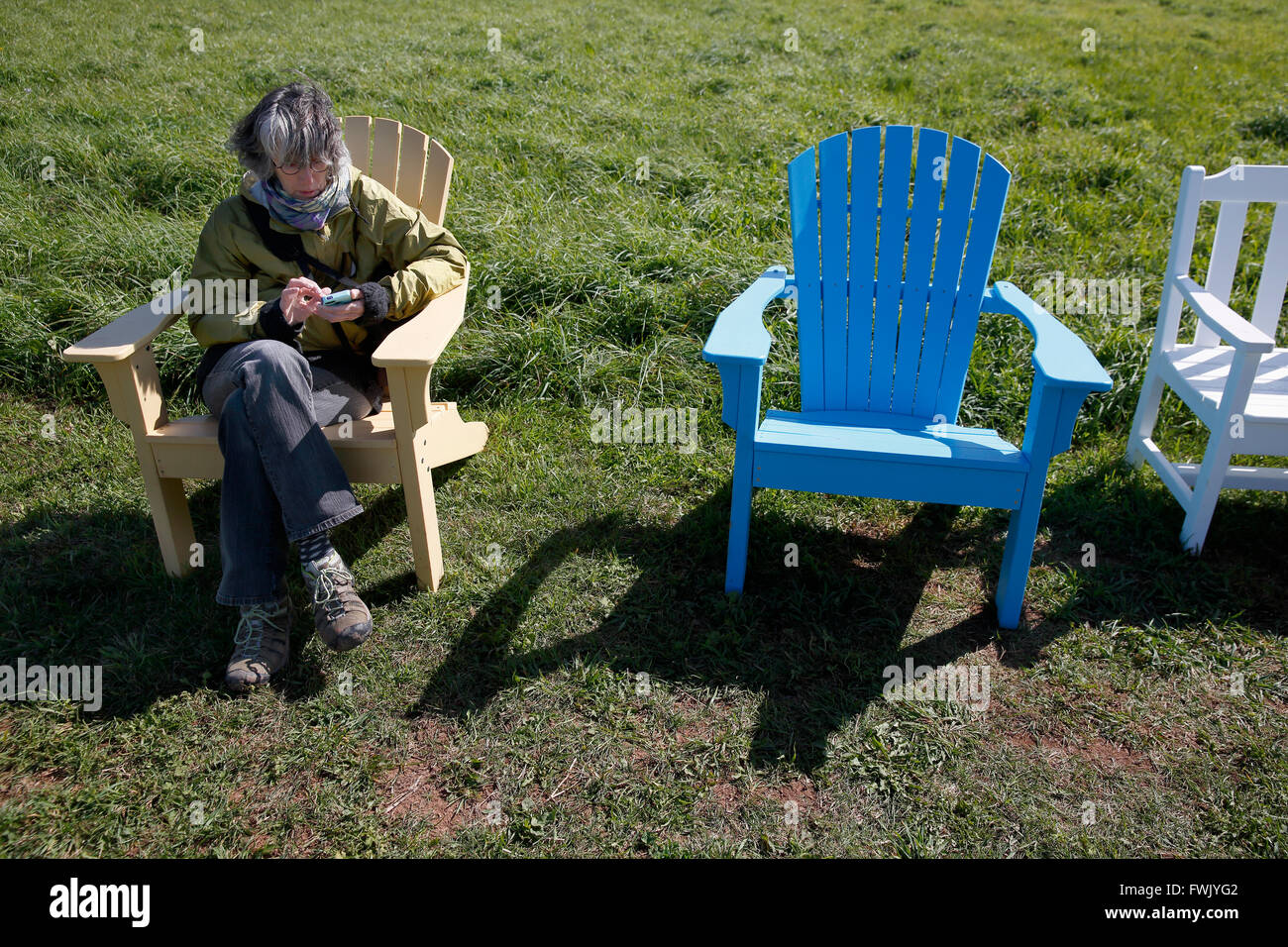 Woman using smart phone in Adirondack chair Stock Photo
