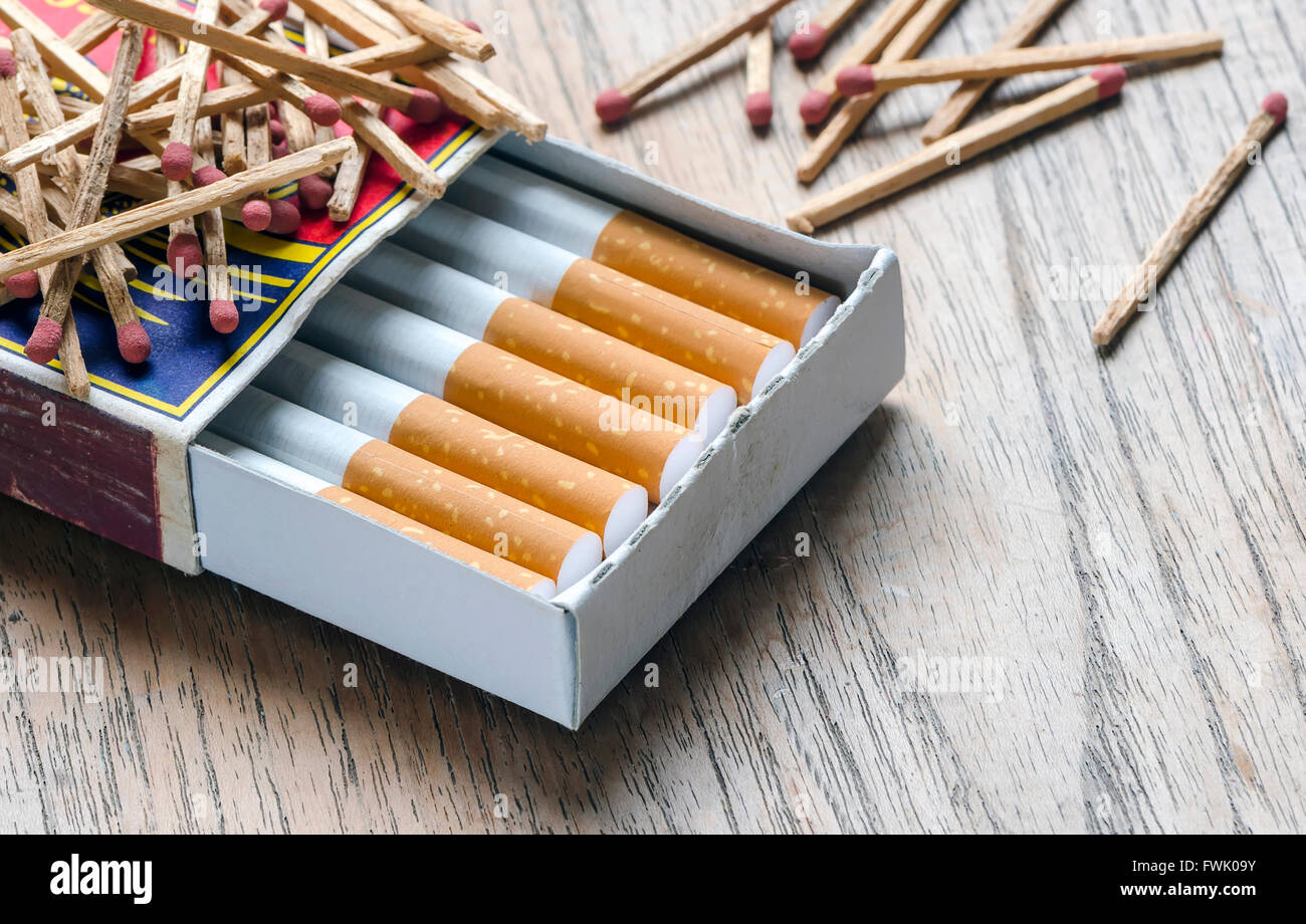 Tobacco cigarette in the box of matches on wooden background Stock