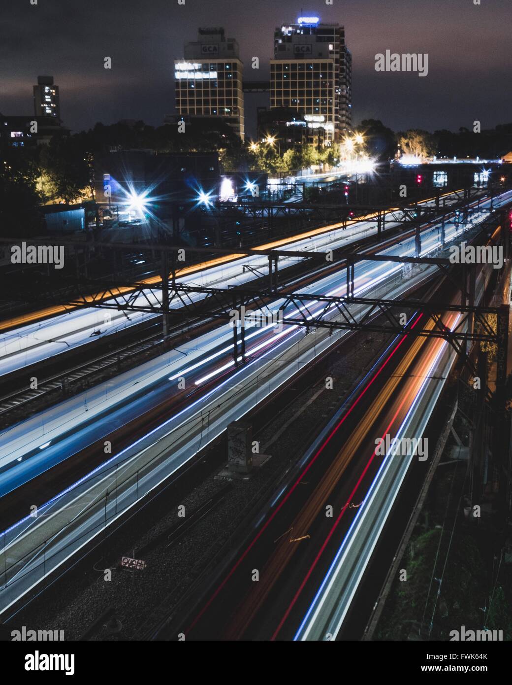Blurred Image Of Trains Moving On Tracks At Night Stock Photo