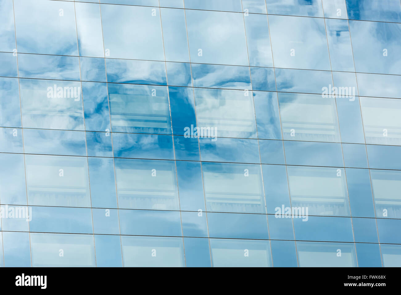 blue sky and clouds reflected in windows of modern office building ...