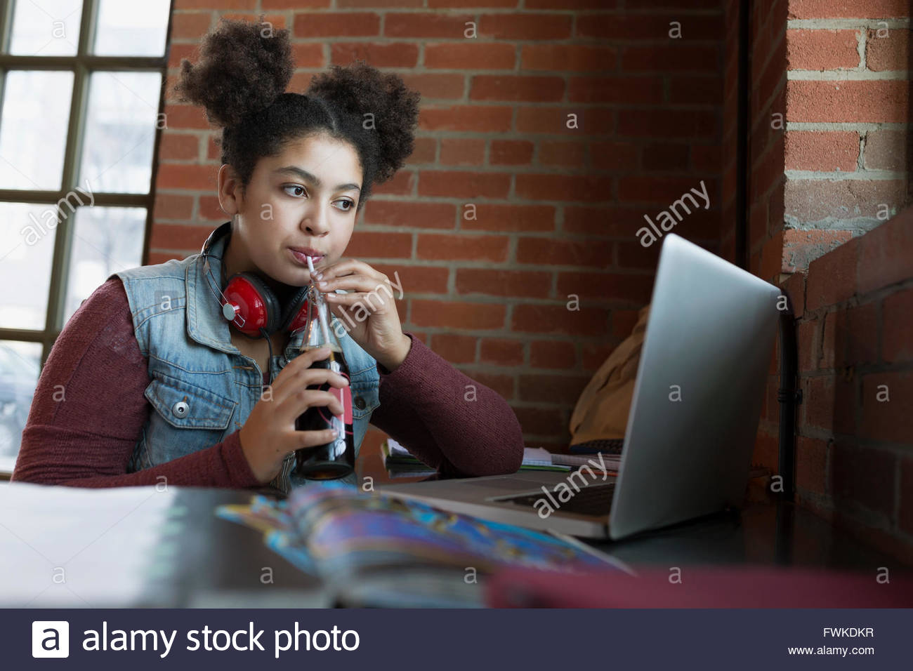 Girl sipping soda from straw at laptop in coffee shop Stock Photo