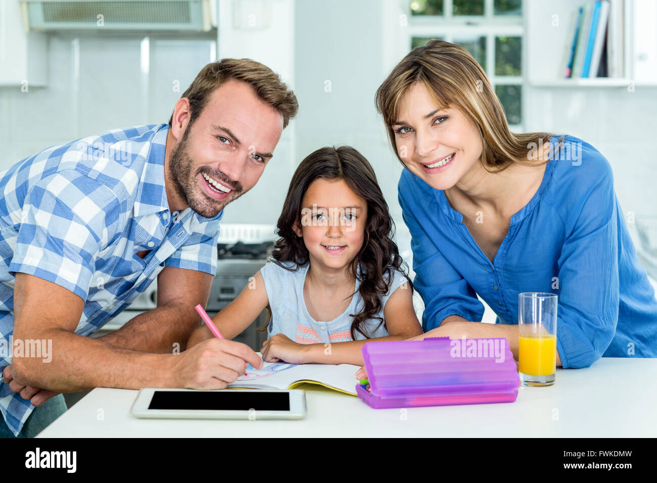 Happy father and mother assisting daughter in homework at home Stock ...