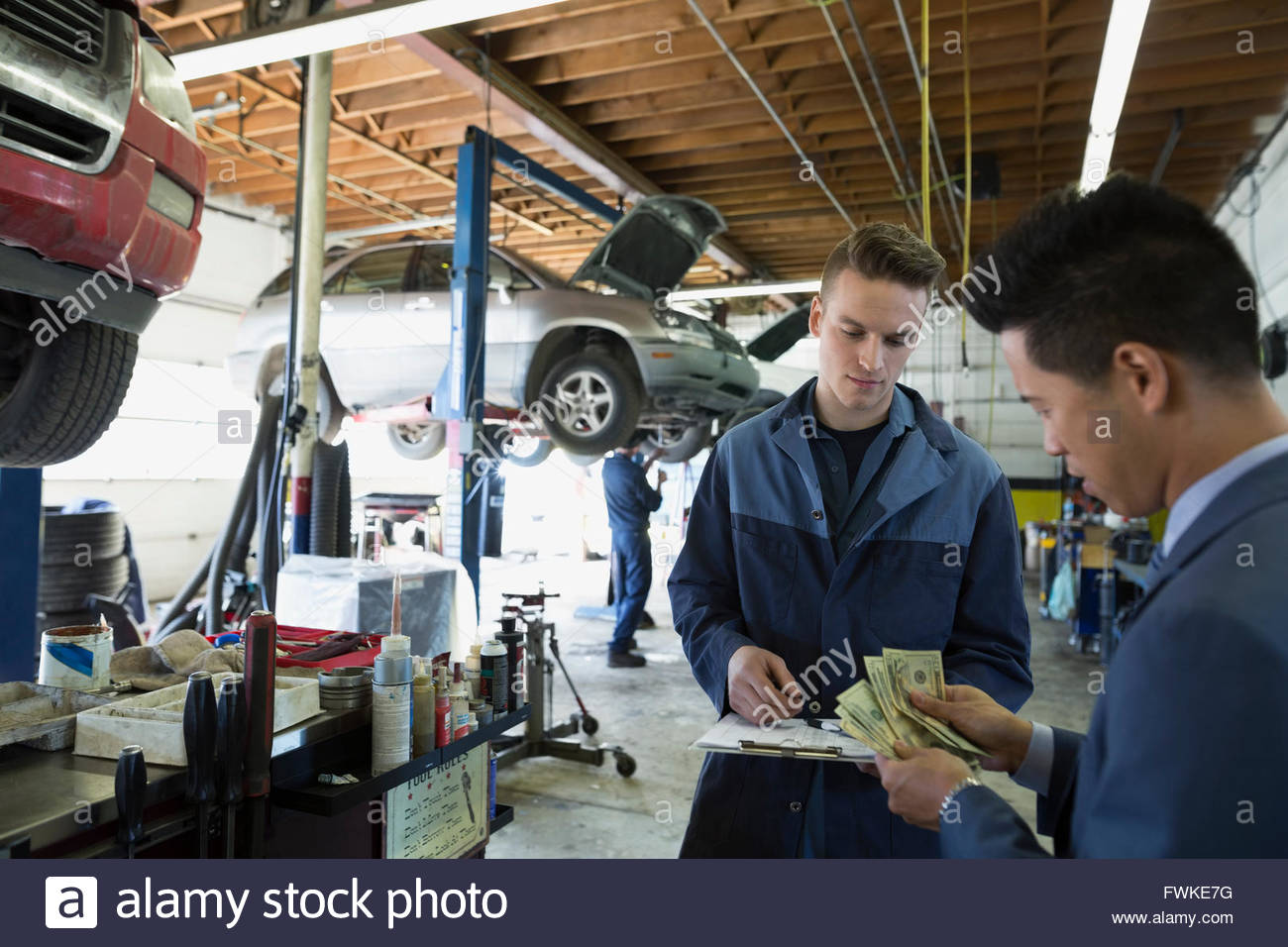 Customer paying mechanic with cash auto repair shop Stock Photo