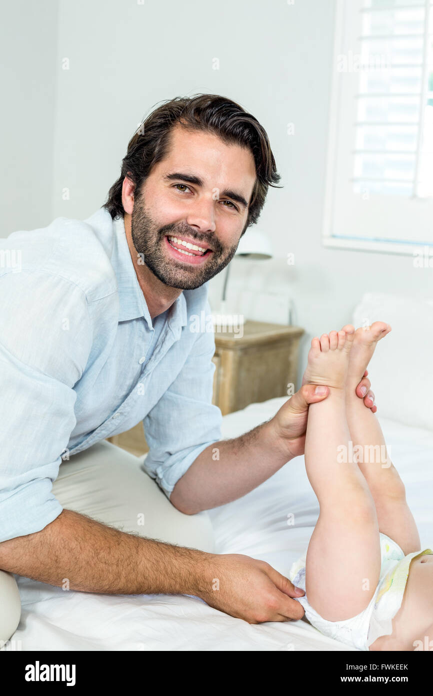 Father changing diaper of son on bed at home Stock Photo Alamy