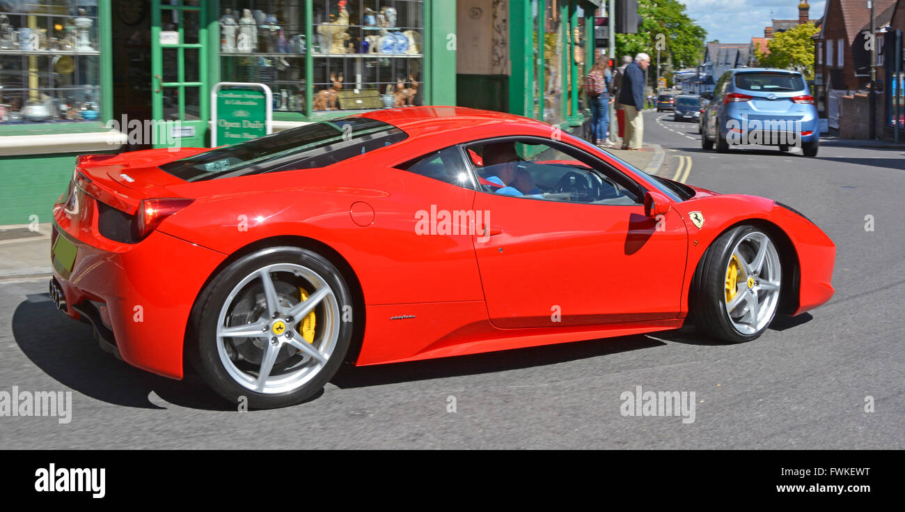 Red Ferrari luxury Italian sports car driving through Lyndhurst in the New Forest Stock Photo