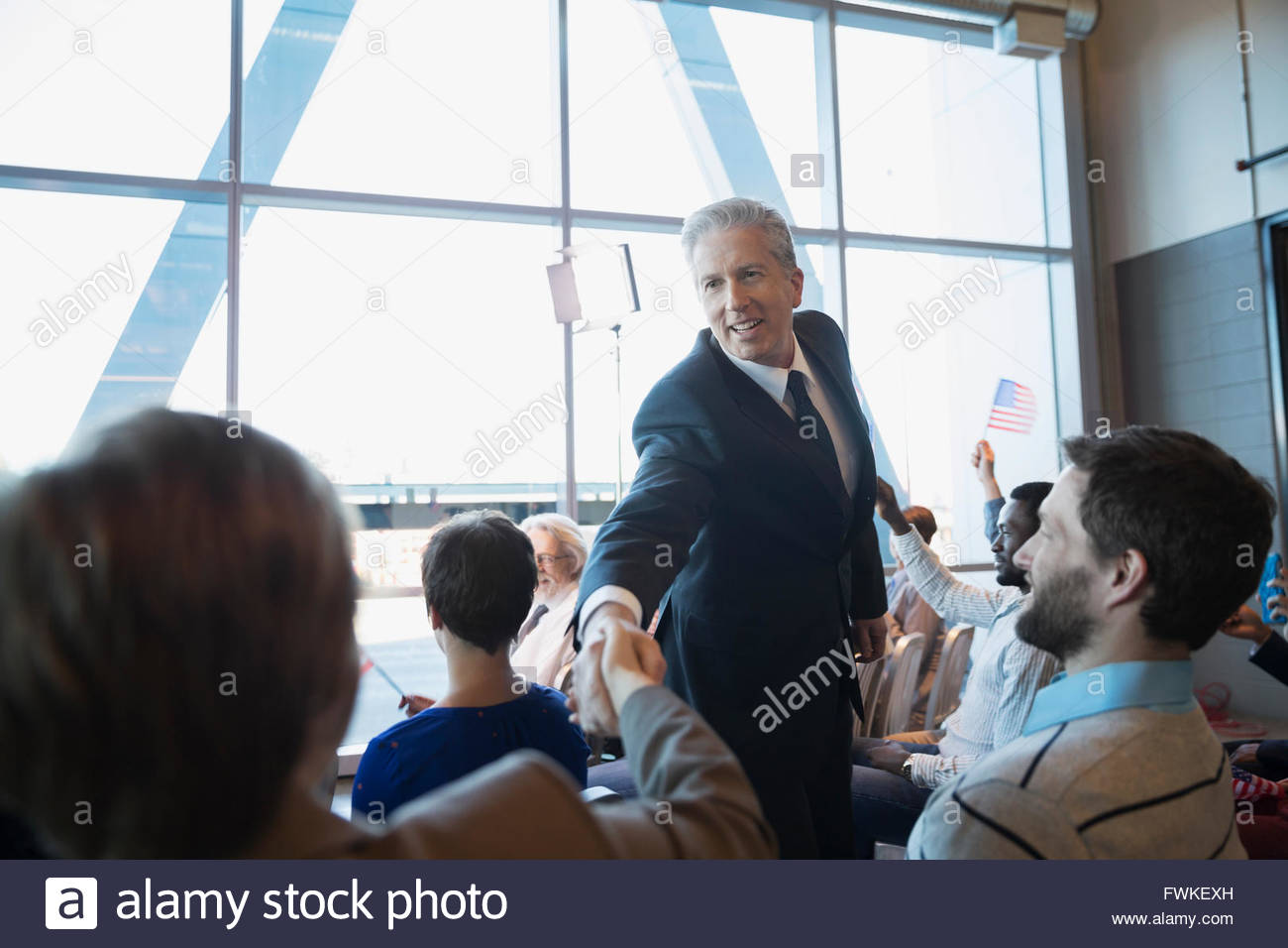Politician shaking hands with audience at political rally Stock Photo