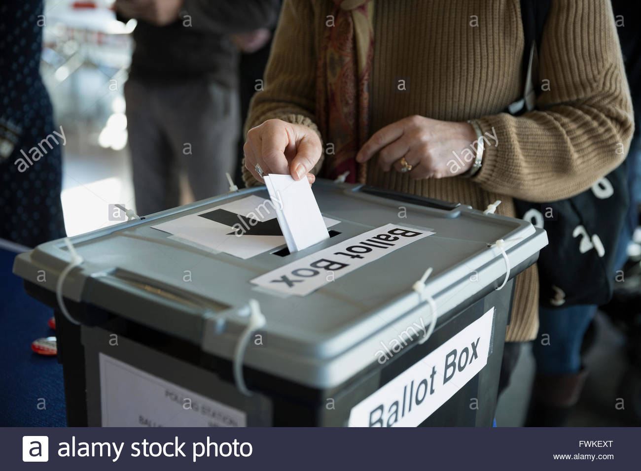 Woman placing ballot in ballot box polling place Stock Photo