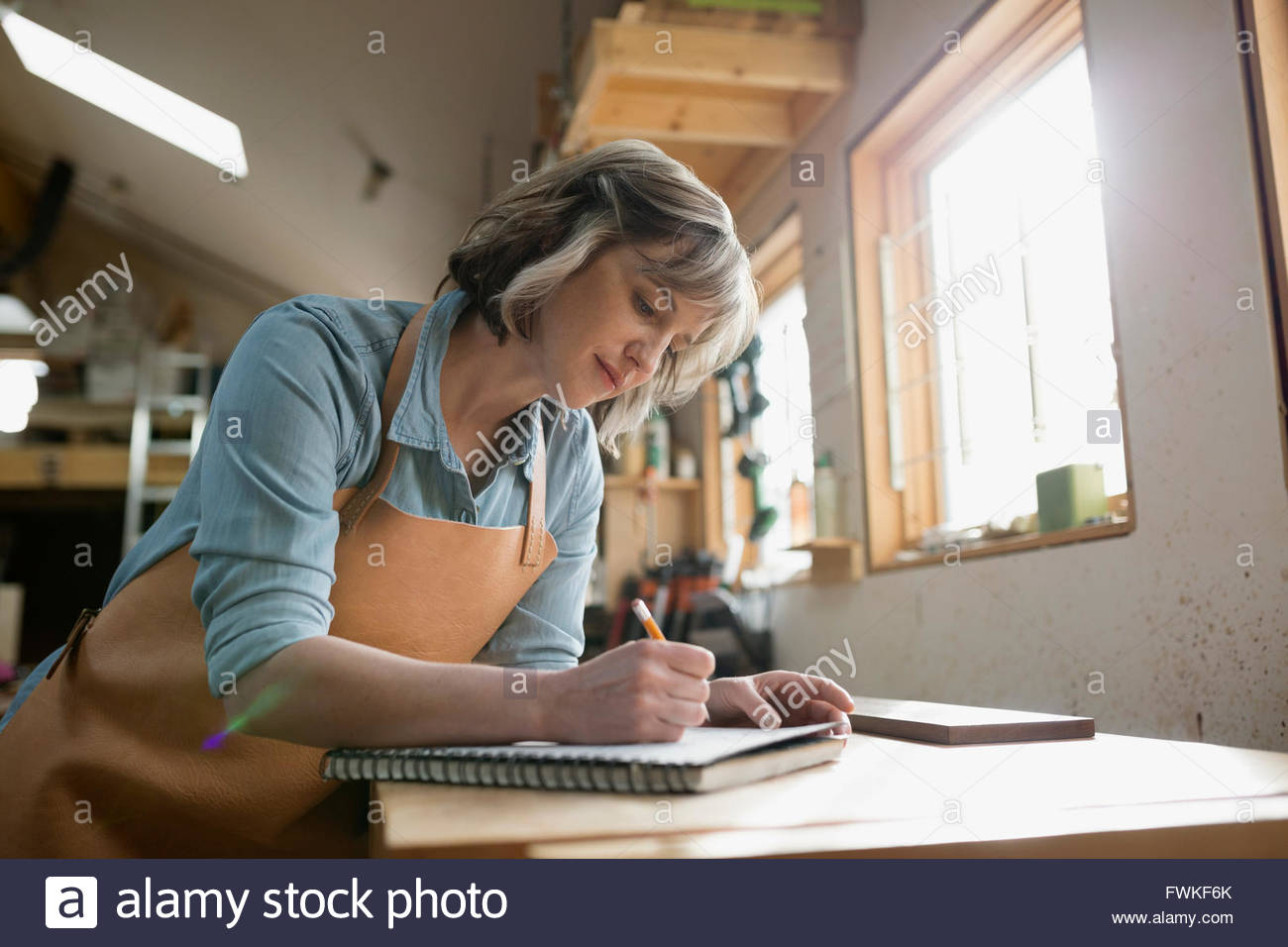 Female carpenter brainstorming and sketching in workshop Stock Photo
