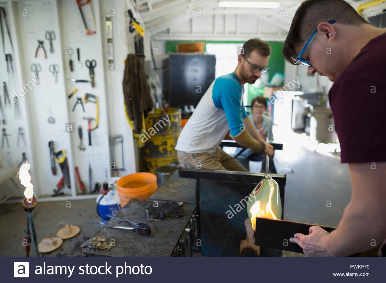 Glassblowers shaping molten glass in workshop Stock Photo