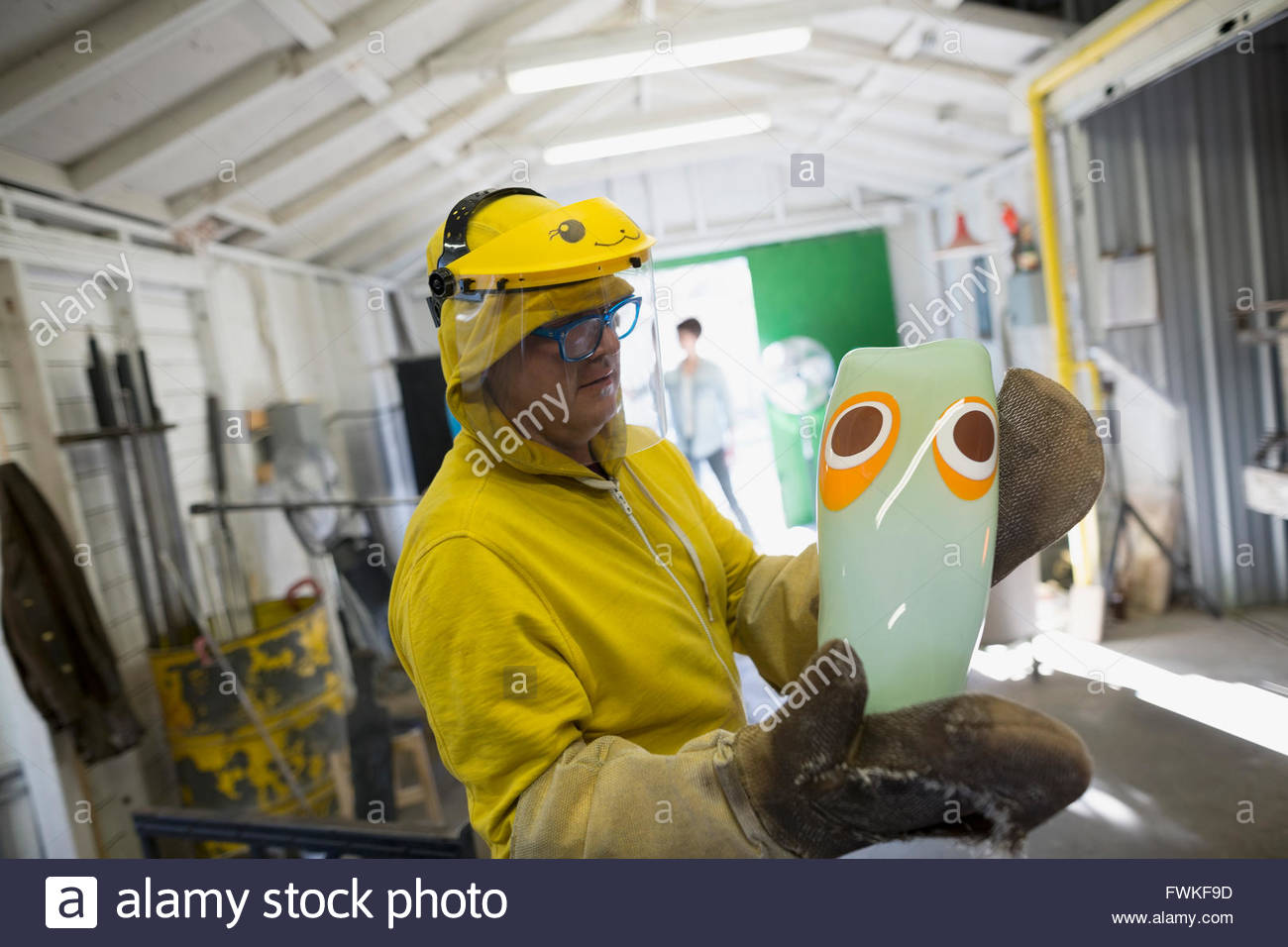 Glassblower in protective workwear holding finished vase Stock Photo
