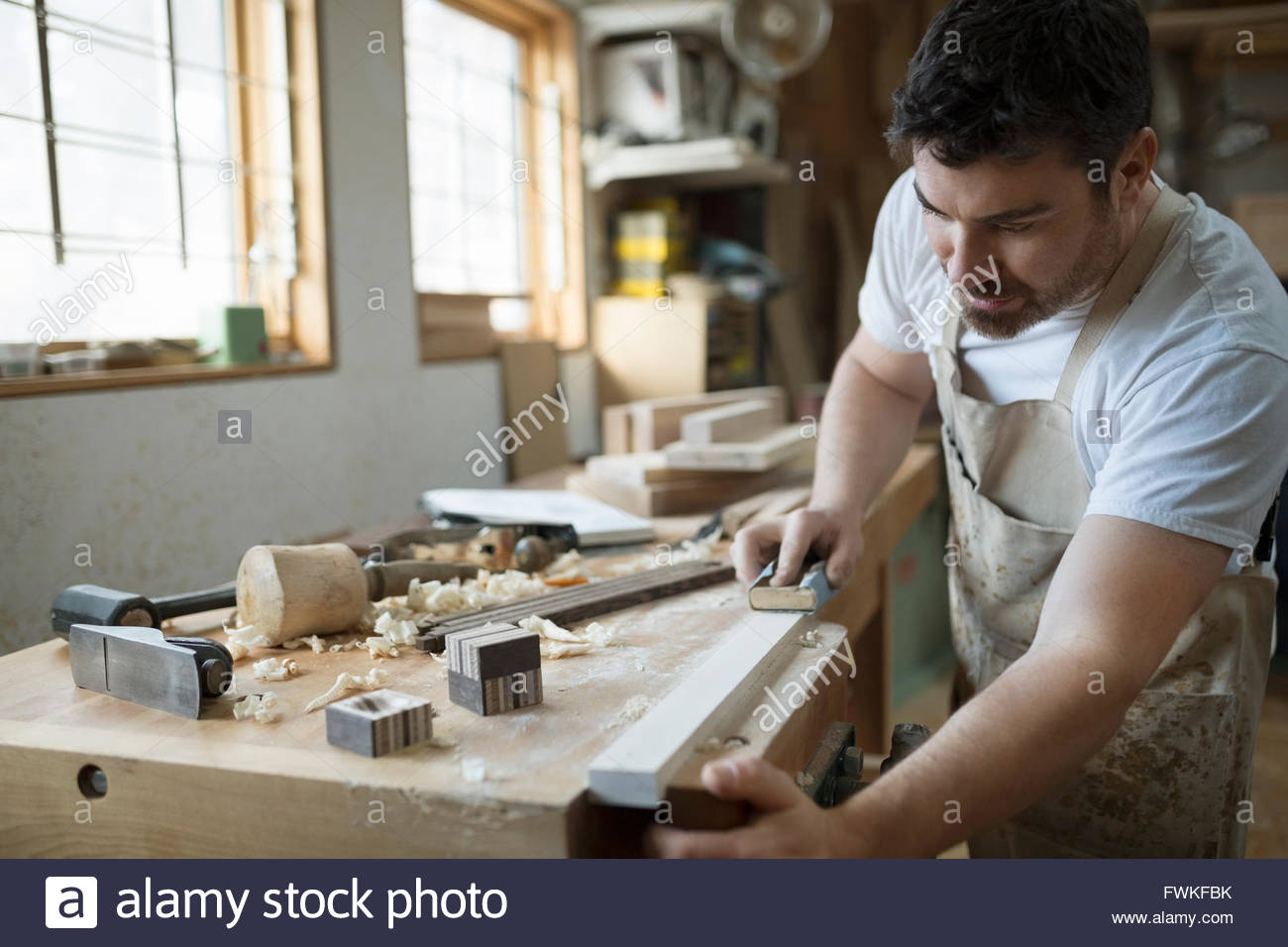 Carpenter sanding wood block in workshop Stock Photo