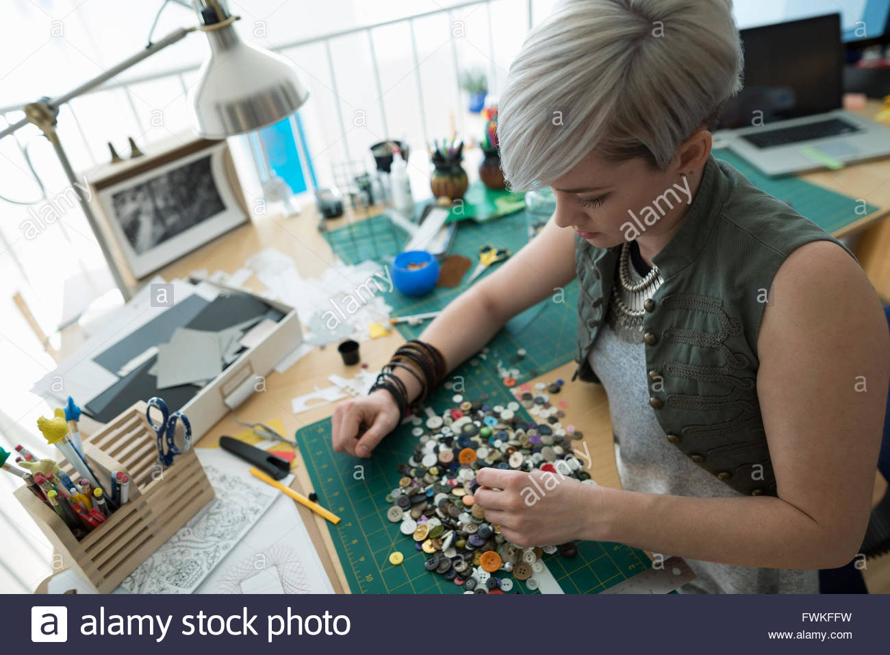 Craftswoman sorting buttons at desk in home office Stock Photo