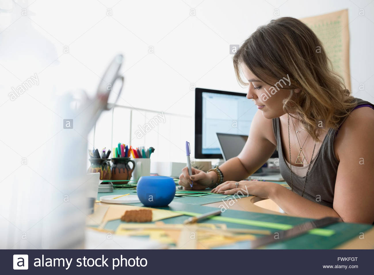 Craftswoman writing at desk in home office Stock Photo