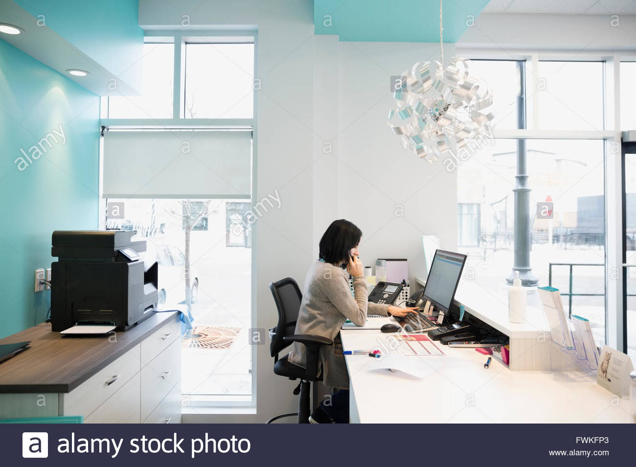 Receptionist answering telephone at clinic front desk Stock Photo Alamy