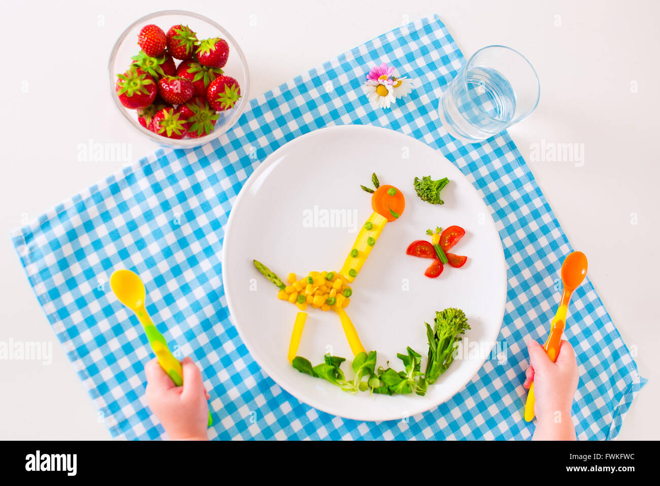 Healthy vegetarian lunch for little kids, vegetables and fruit served as animals, corn, broccoli, carrots and fresh strawberry Stock Photo