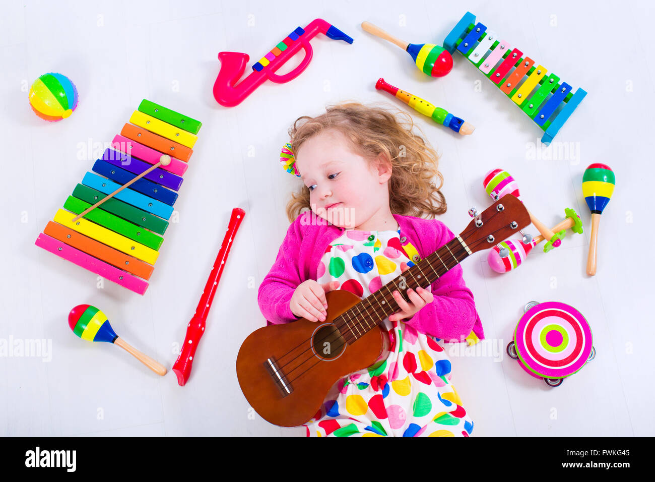 Child with music instruments. Musical education for kids. Colorful wooden art toys for kids. Little girl playing music. Stock Photo