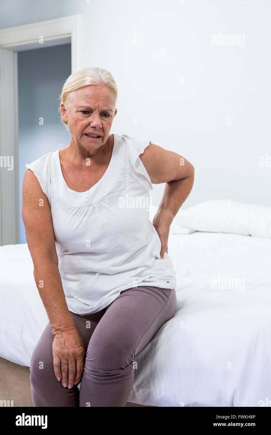 Senior woman suffering from back pain while sitting in bedroom Stock ...