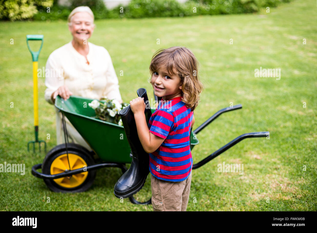 Boy holding wellington boots besides granny in yard Stock Photo