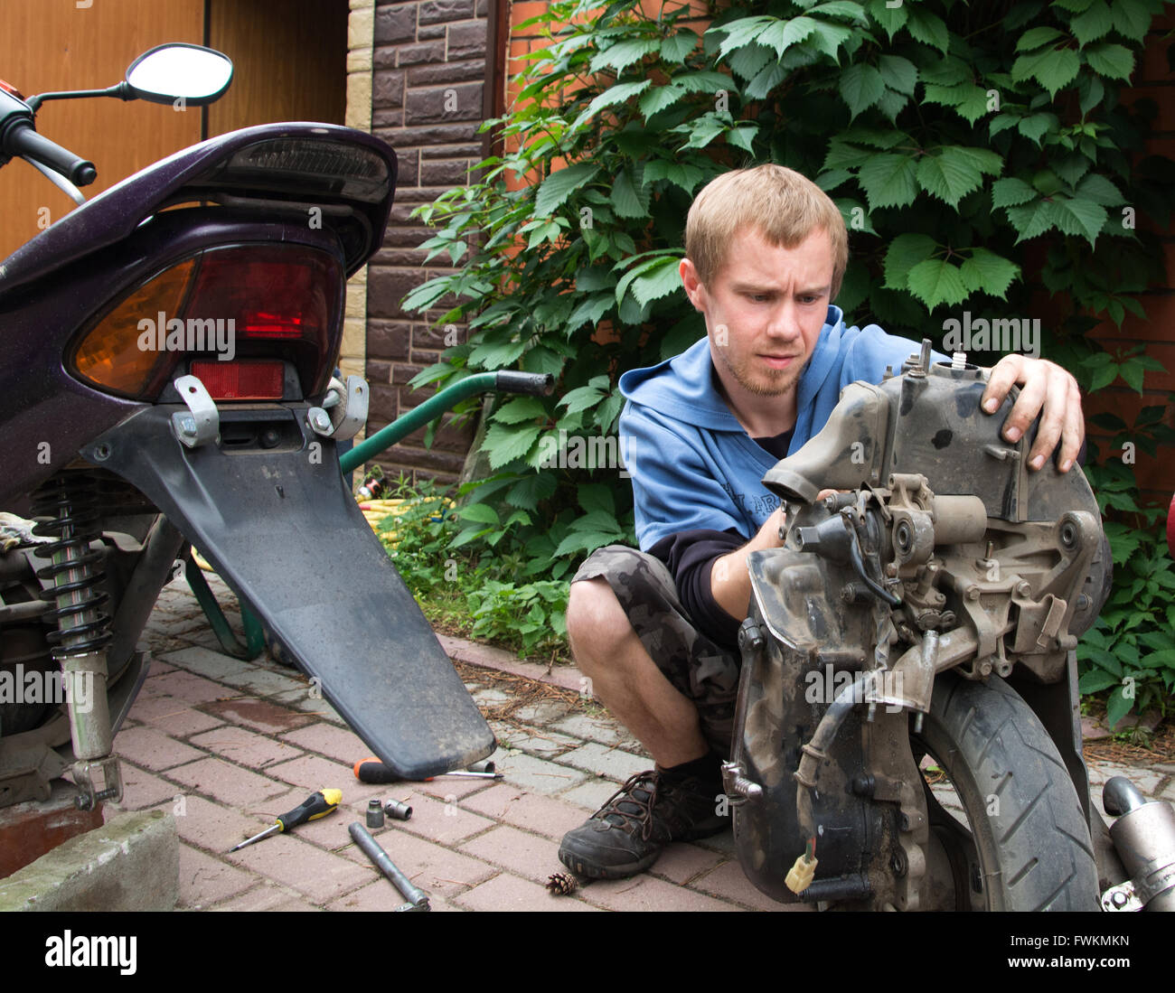 boy repairs motor scooter Stock Photo Alamy