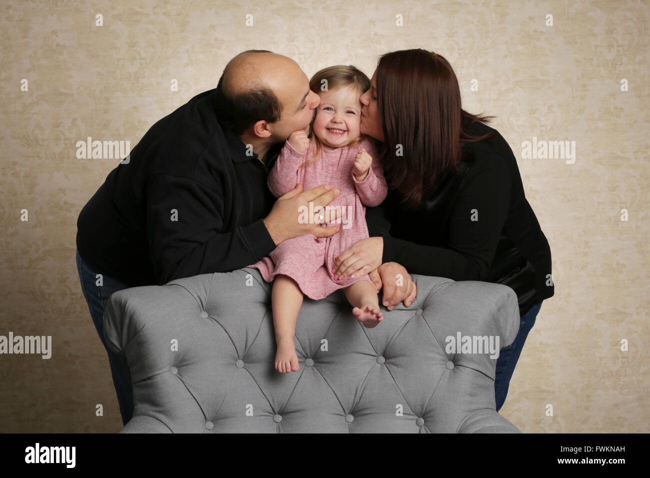 Parents kissing their child Stock Photo Alamy