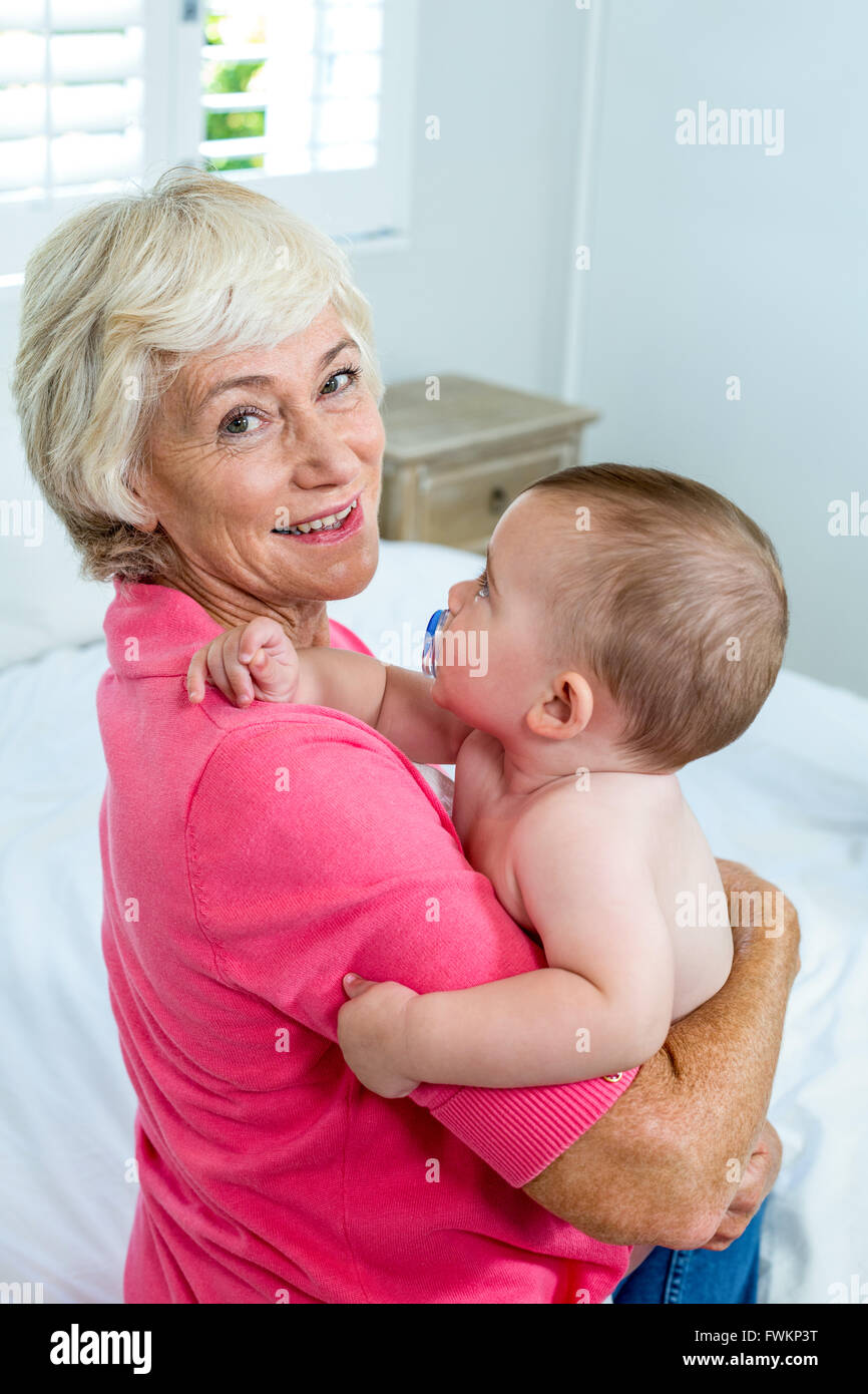 Grandmother carrying baby boy on bed Stock Photo Alamy