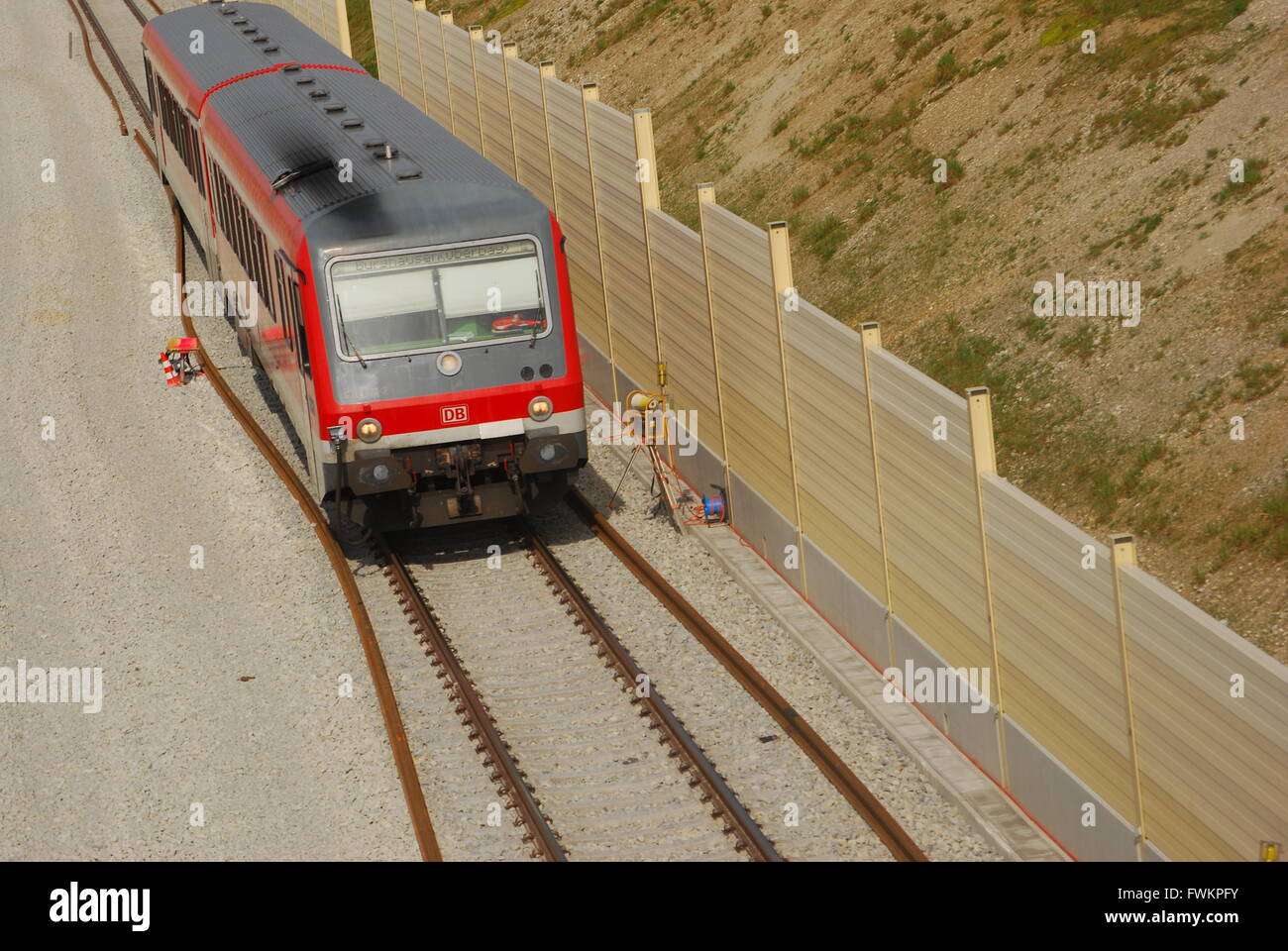 Local train drives along noise reduction wall at a construction site