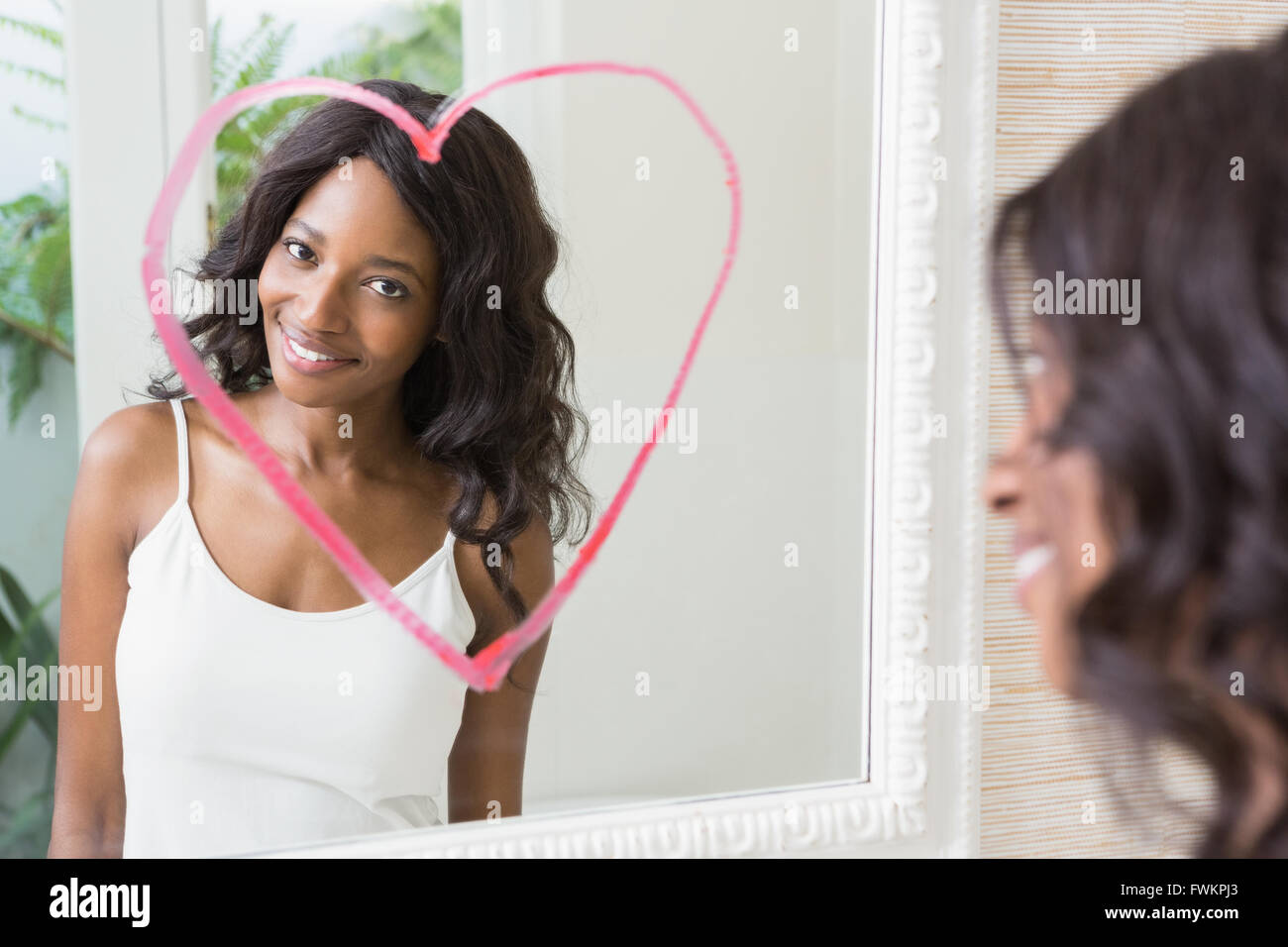 Beautiful young woman looking in the mirror Stock Photo - Alamy
