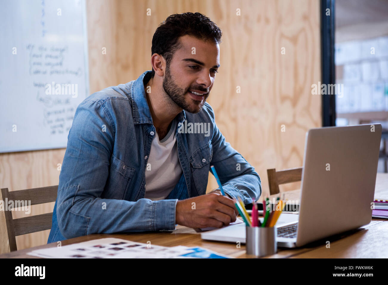 Man writing note on diary while using laptop Stock Photo - Alamy