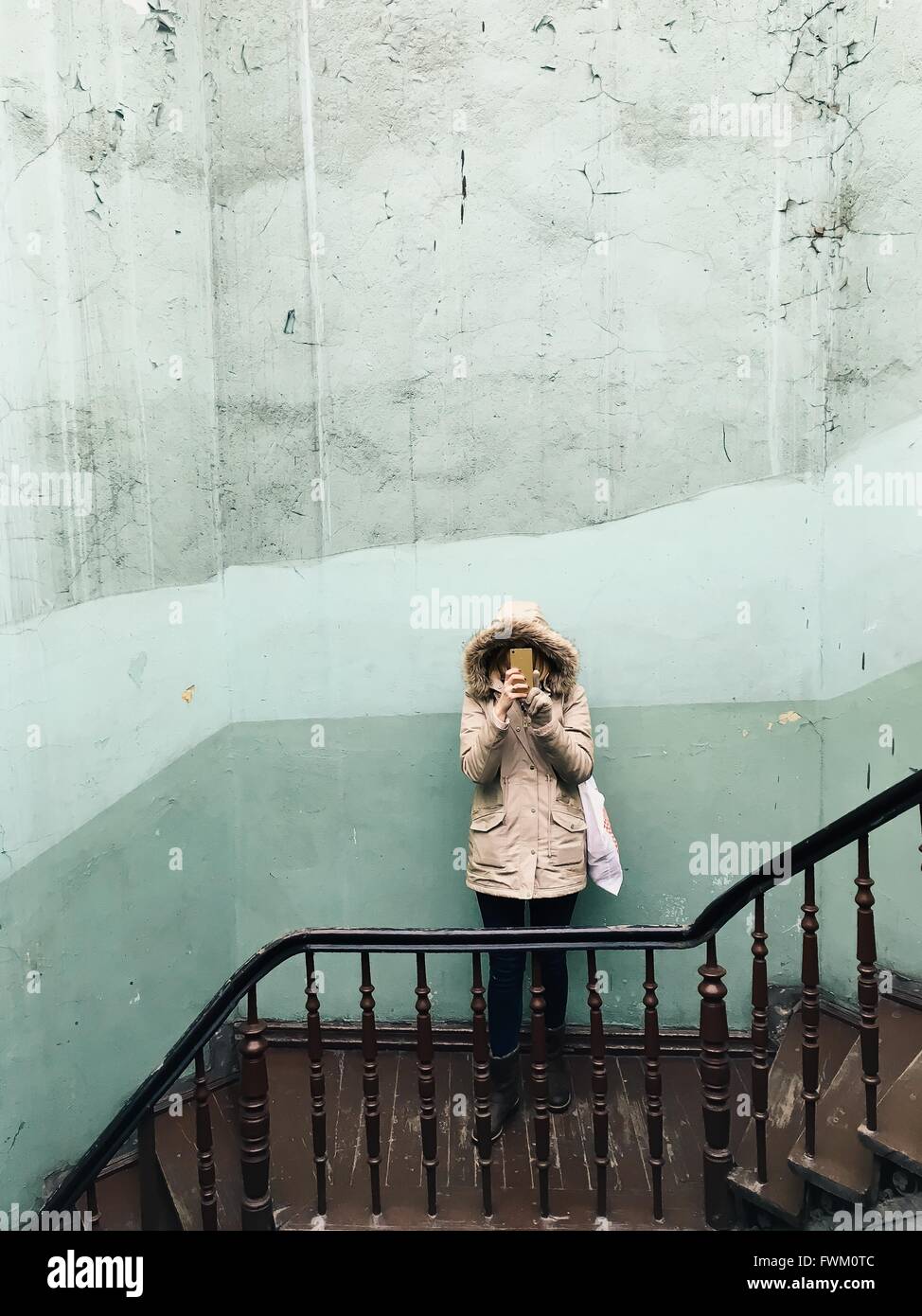 High Angle View Of Woman Holding Smart Phone Against Wall On Steps Stock Photo