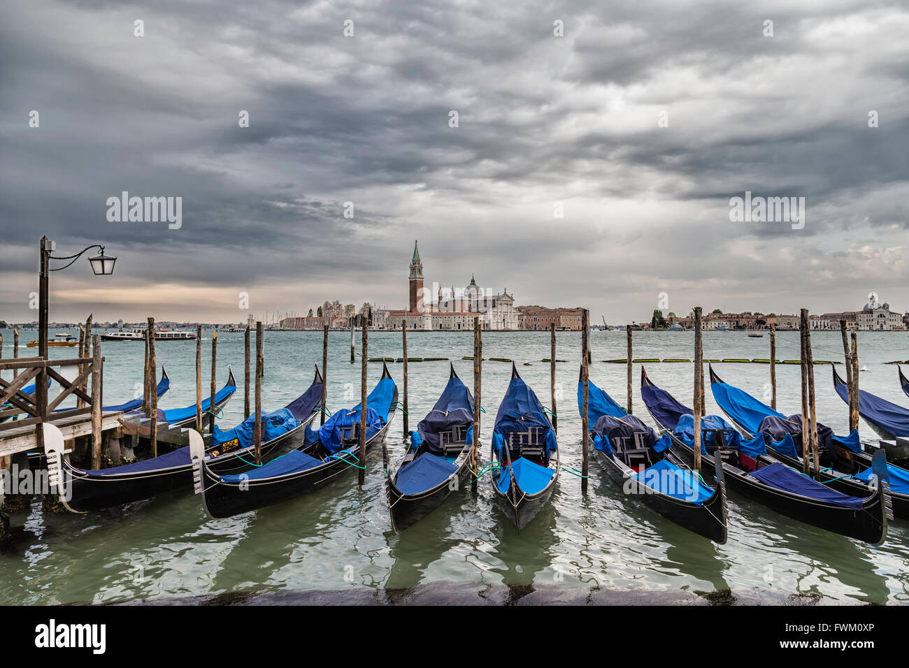 Dramatic view of Venice with row of gondolas docked to the poles on the Grand Canal around Piazza San Marco in Venice, Italy Stock Photo