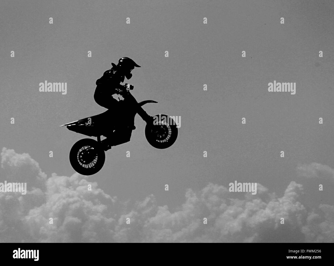 Side View Of Motocross Racer Performing Mid-Air Against Sky Stock Photo