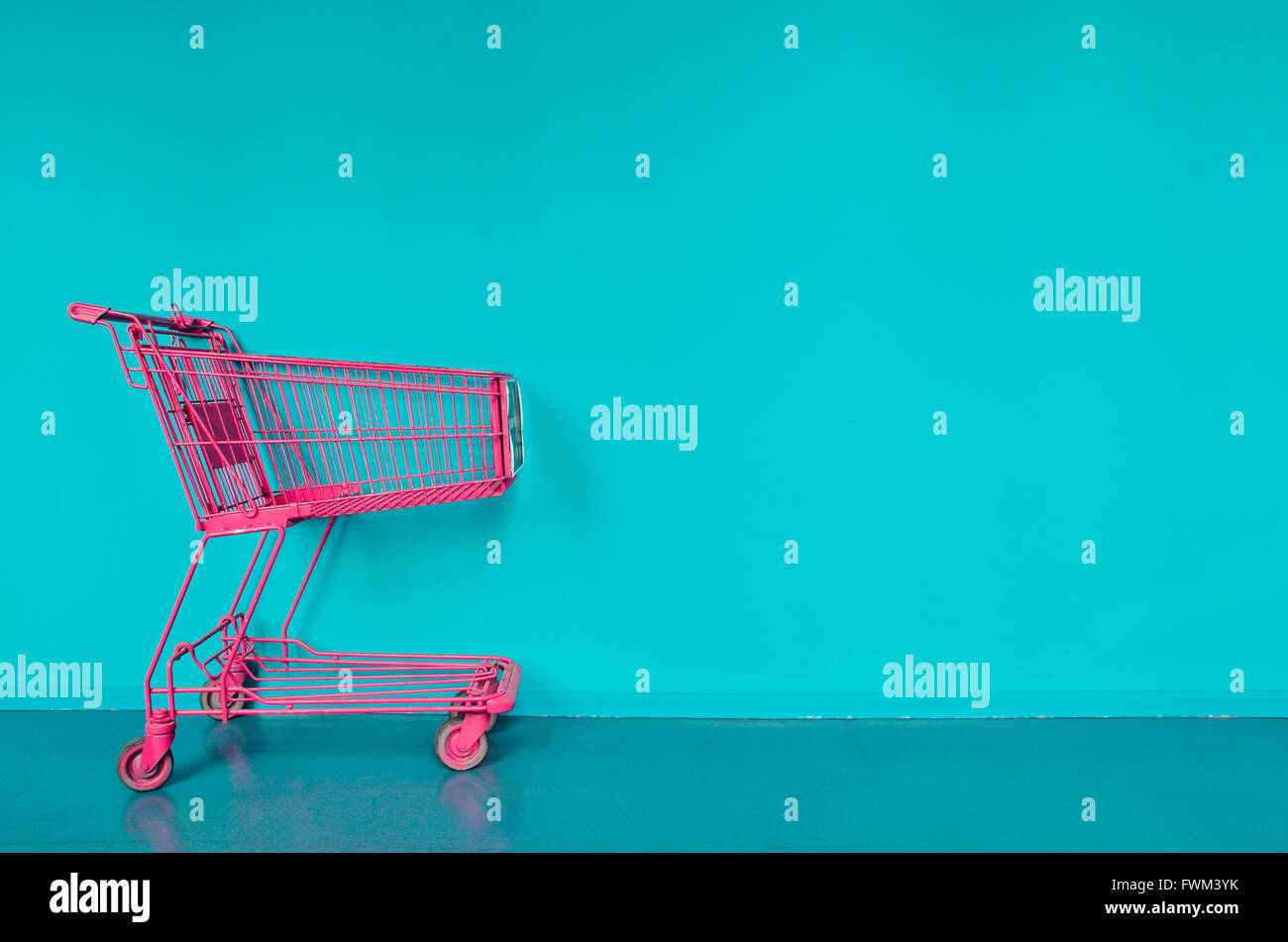 Pink Shopping Cart Against Turquoise Wall Stock Photo
