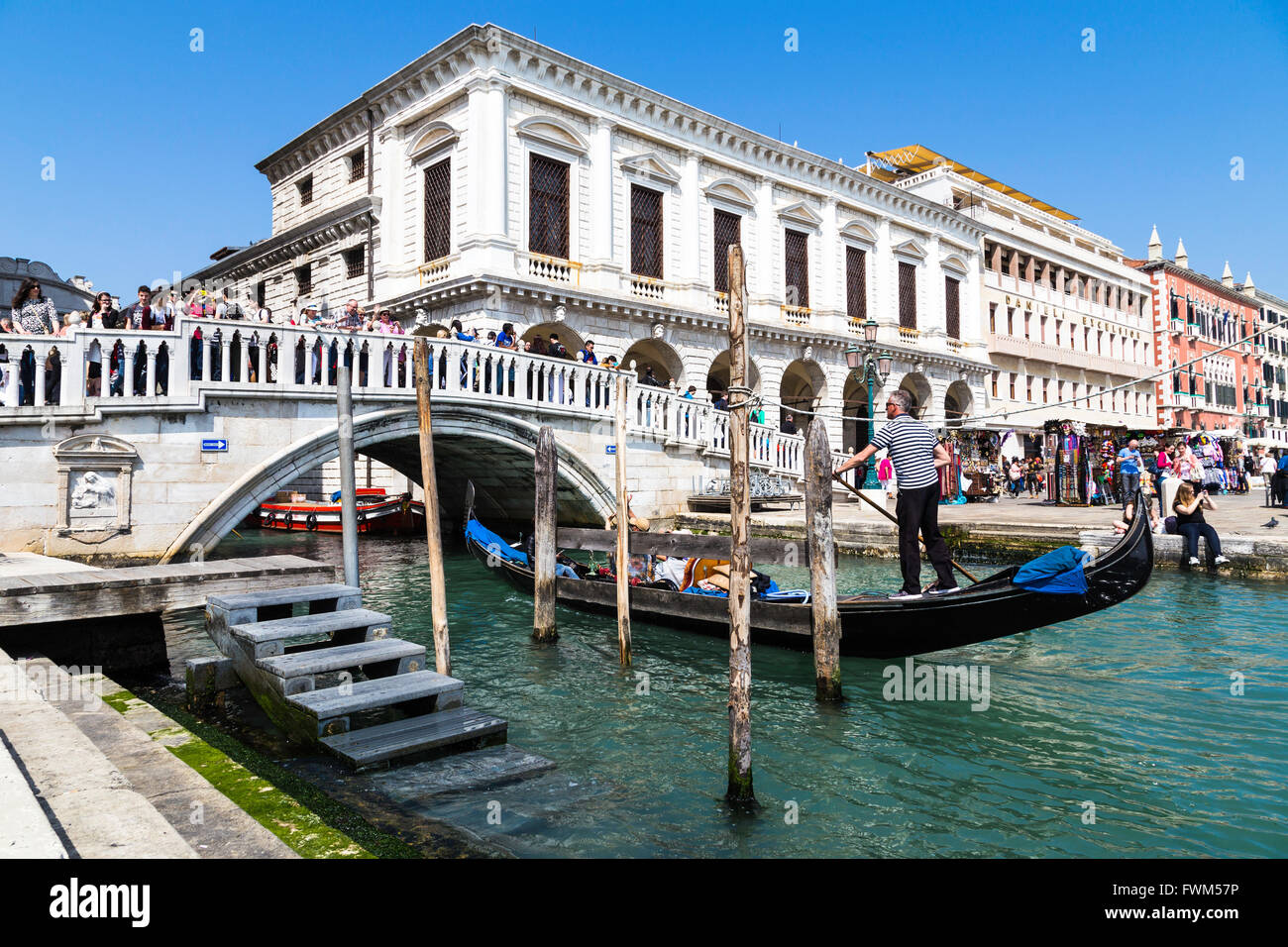 Traditional gondolier rowing through the channels. Gondola trip during the ride in Venice Italy. Stock Photo