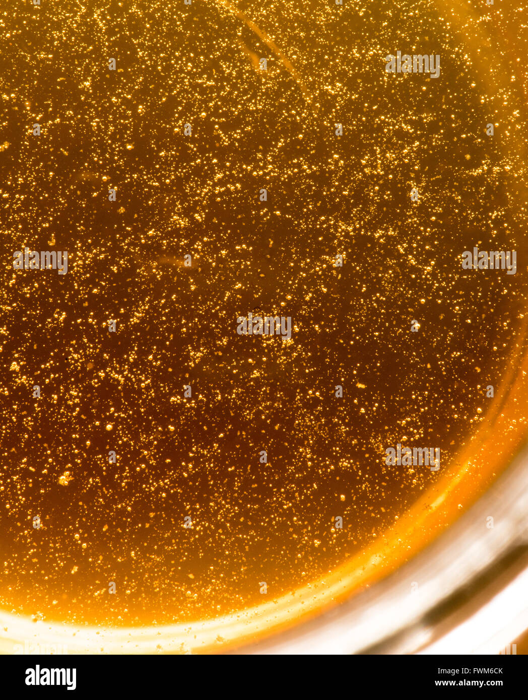 A close up freshly poured honey in a jar. There are quite a few air