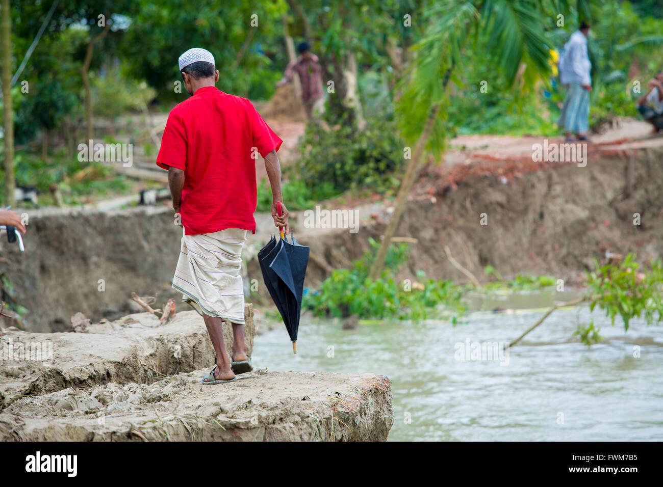 A red cloth man walking by his home at Char areas, Borishal, Bangladesh
