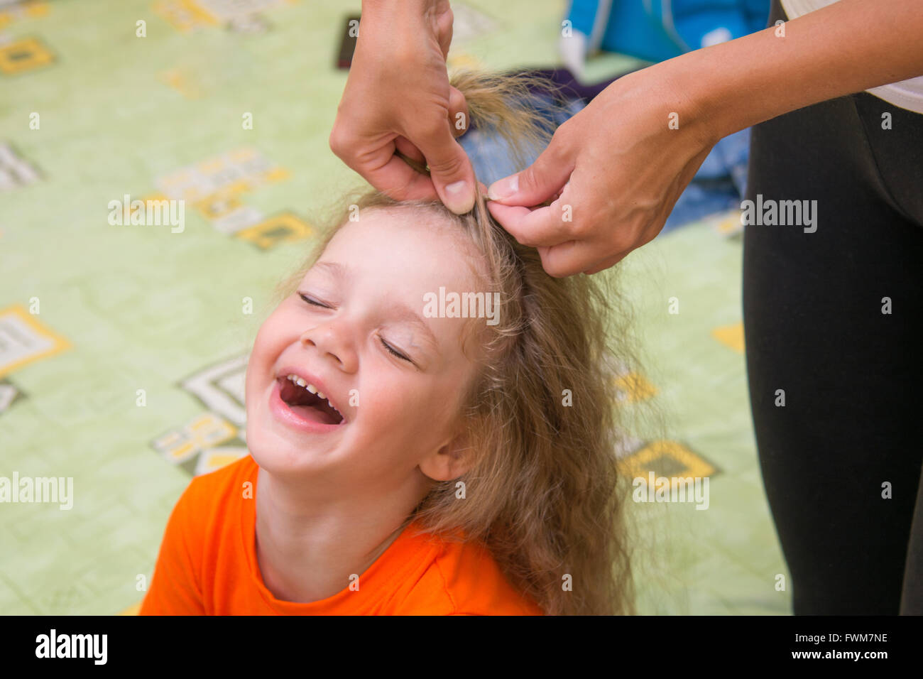 A girl of four years old sitting happily when she do her hair Stock Photo
