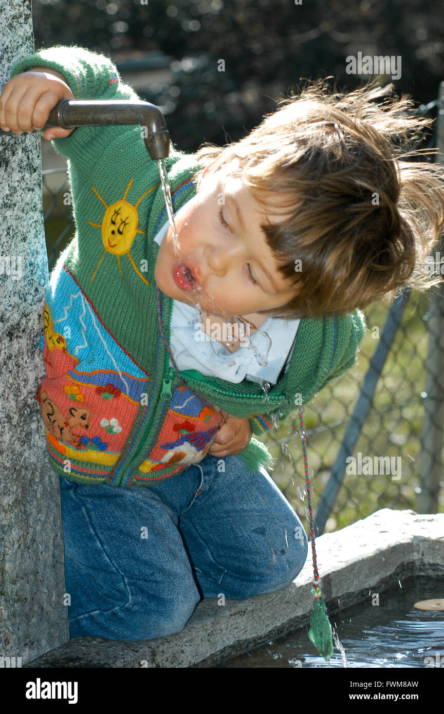 A little boy drinking from a water fountain in the park Stock Photo Alamy