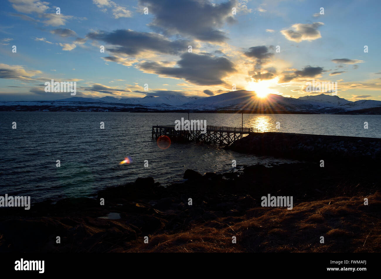 beautiful sunset over snowy mountain, fjord and pier Stock Photo - Alamy