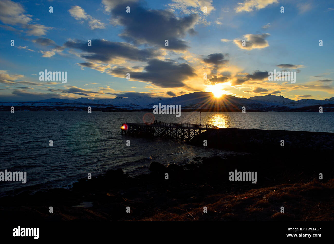 beautiful sunset over snowy mountain, fjord and pier Stock Photo - Alamy