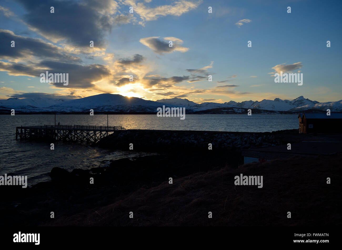 beautiful sunset over snowy mountain, fjord and pier Stock Photo - Alamy